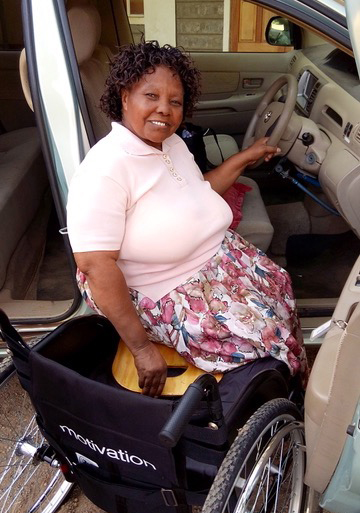 An older woman using a wheelchair, about to get on a vehicle.