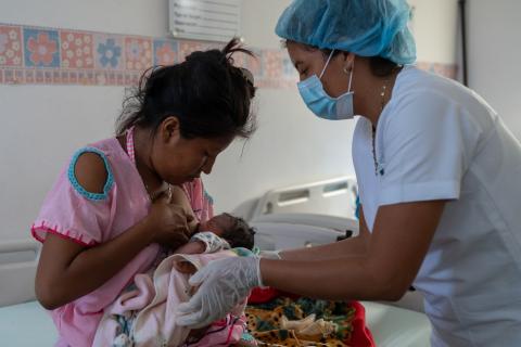  A health worker assists a mother to help facilitate successful breastfeeding at the ESE Hospital de Nazareth in Alta Guajira, Colombia. Photo taken in July 2020