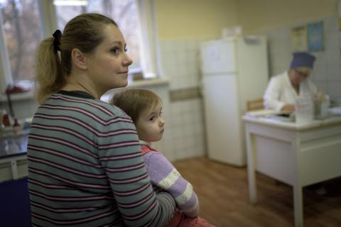 A mother waits with her small child for polio vaccination in Ukraine